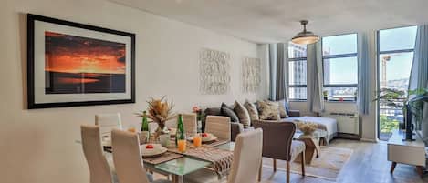 Un salon moderne avec un coin repas, de grandes fenêtres et une vue sur la ville.