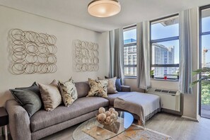 A modern living room with a grey sofa, a glass coffee table, and decorative wall art.