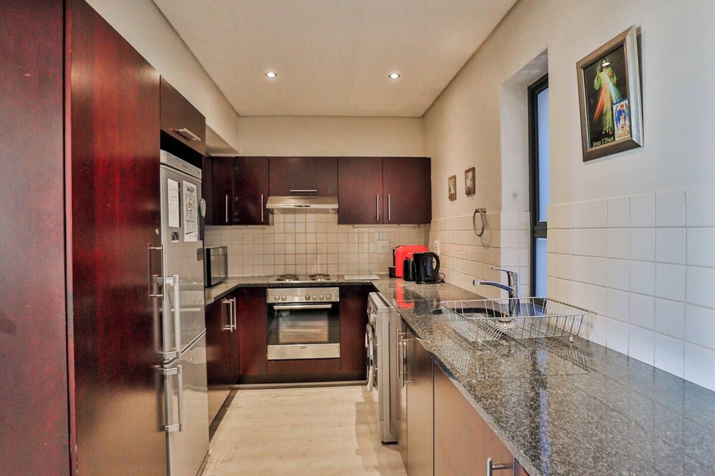 Una cocina moderna con electrodomésticos de acero inoxidable, armarios de madera oscura y encimera de granito.