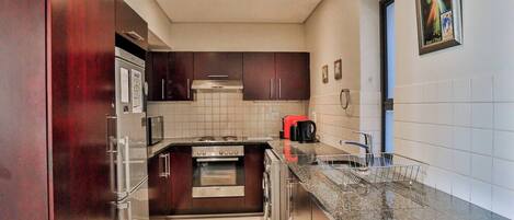 Eine moderne Küche mit Edelstahlgeräten, dunklen Holzschränken und einer Arbeitsplatte aus Granit.