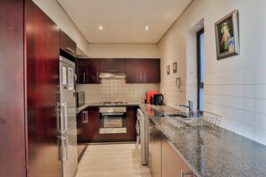 A modern kitchen with stainless steel appliances, dark wood cabinets, and a granite countertop.