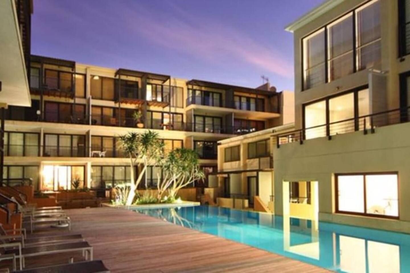 A multi-story hotel with a swimming pool, outdoor seating, and a well-lit courtyard.