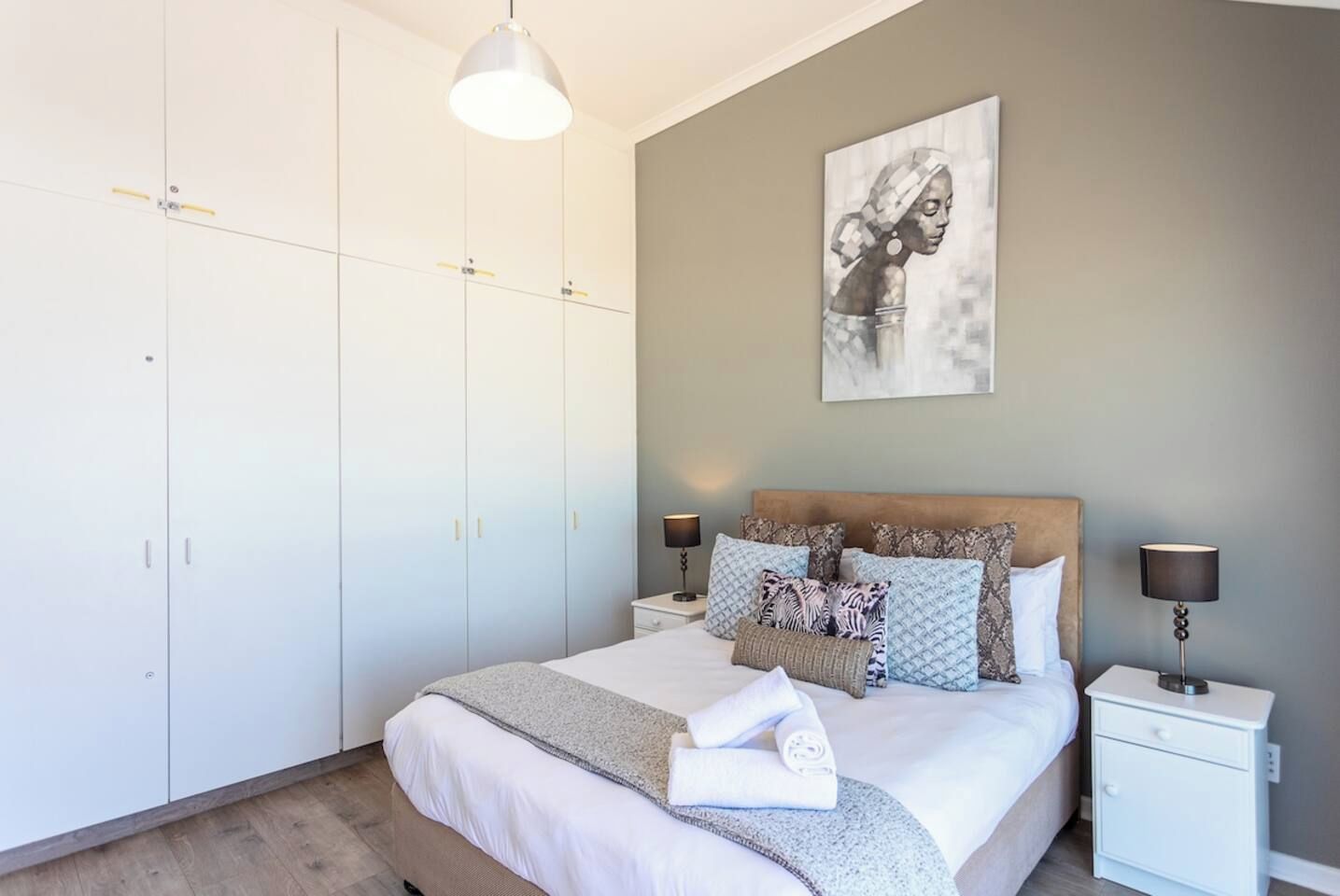 Ein Schlafzimmer mit Bett, Nachttischen, einem Kleiderschrank und einem Bild an der Wand.