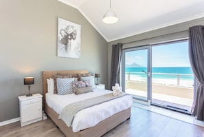 Una camera da letto con un letto, comodini, un quadro e vista sulla spiaggia.