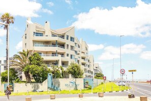 Un hotel a più piani con balconi, una palma e un cartello con la scritta 'SEA SPRAY'.