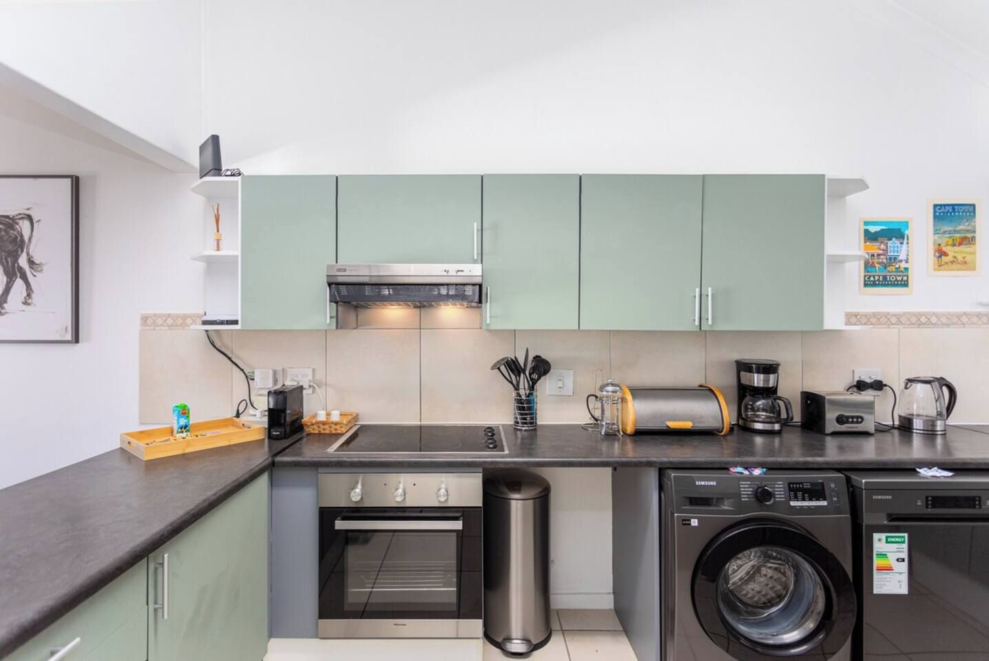 A compact kitchen with a microwave, toaster, coffee maker, and a washing machine.