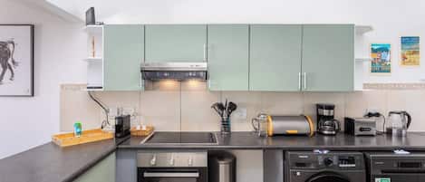 A compact kitchen with a microwave, toaster, coffee maker, and a washing machine.
