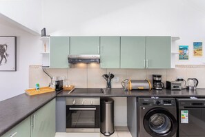 A compact kitchen with a microwave, toaster, coffee maker, and a washing machine.
