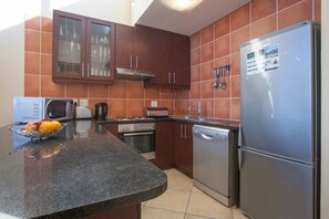 A modern kitchen with granite countertops, stainless steel appliances, and wooden cabinets.