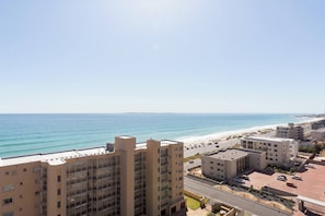 Paesaggio costiero con edifici alti, una spiaggia e cielo sereno.