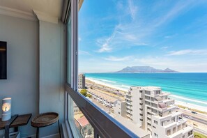 A room with a large window overlooking a beach and cityscape.