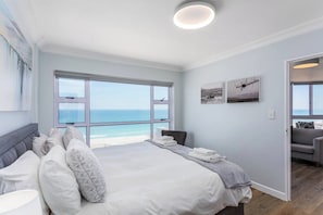 Una camera da letto con un letto grande, vista sulla spiaggia e una porta che dà su un'altra stanza.
