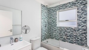 A modern bathroom with a glass shower enclosure, a white toilet, and a sink with a mirror. - Ocean View A1101 by Ctha (Cape Town)