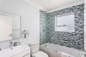 Un bagno moderno con box doccia in vetro, un water bianco e un lavabo con specchio.