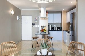 A modern kitchen with white cabinets, stainless steel appliances, and a central island with a fruit bowl.