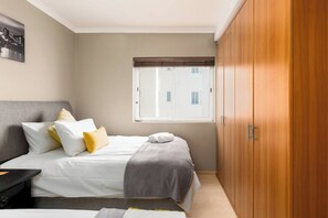 A bedroom with a bed, bedside table, wardrobe, and a window.