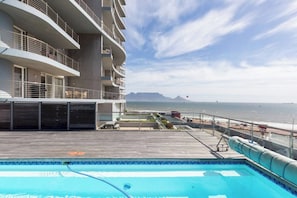 Una piscina sul tetto con vista sull'oceano e un edificio con balconi.