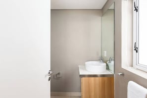 Un bagno con un lavandino bianco, uno specchio e un armadietto in legno.