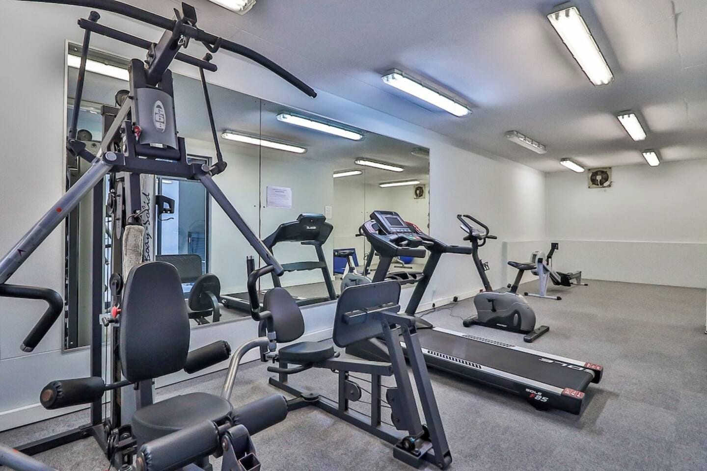 A gym with cardio equipment, weight machines, and a mirrored wall.