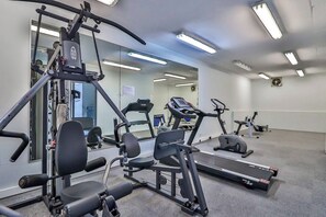 Une salle de sport équipée de machines de cardio, d’appareils de musculation et dotée d’un mur recouvert de miroirs.