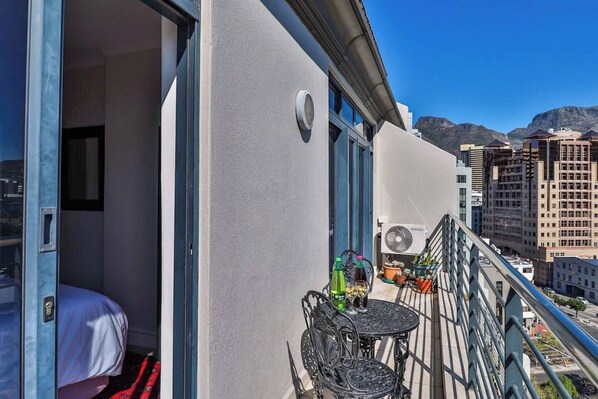 Un balcon avec un lit, une table avec des bouteilles et un climatiseur Samsung.
