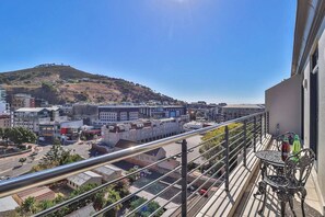Un balcone con vista su un panorama urbano, che include edifici e una collina.