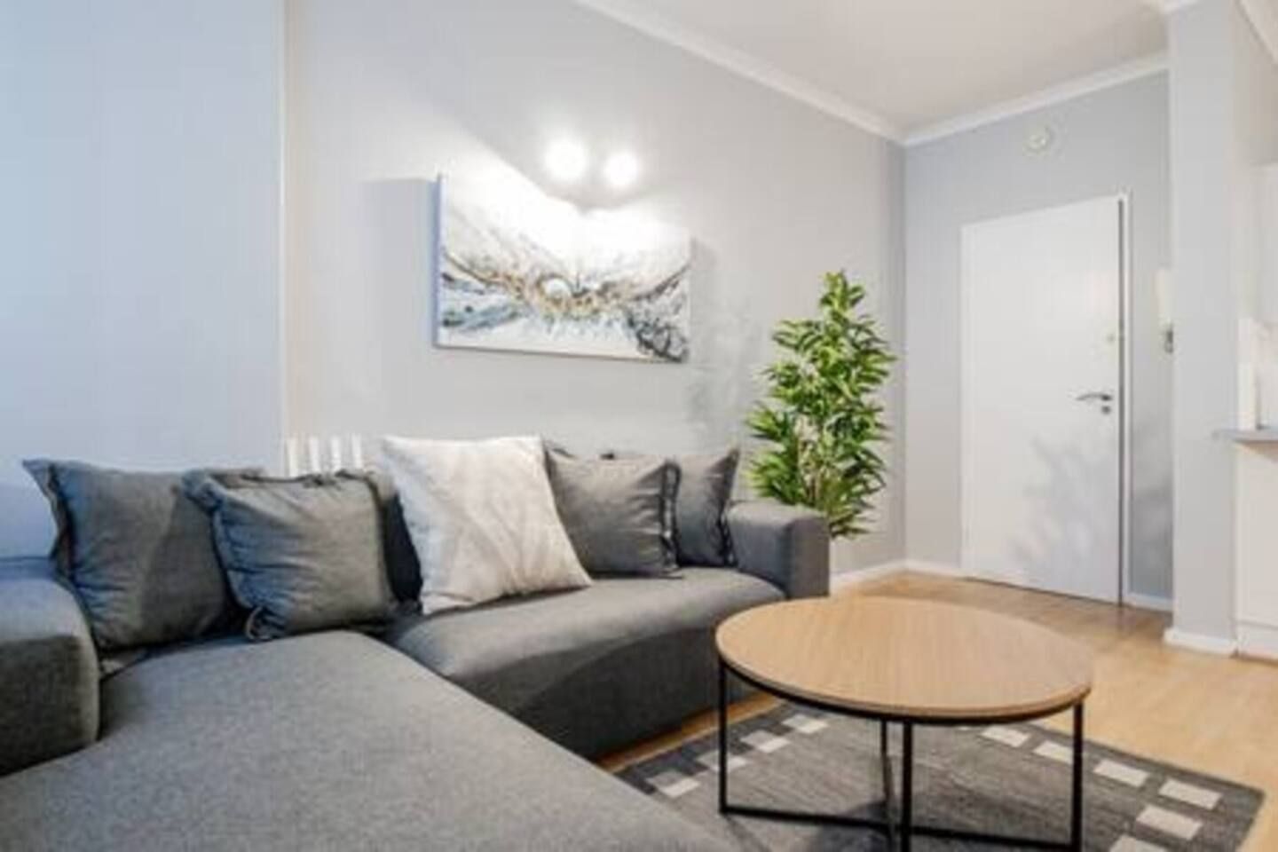A modern living room with a grey sofa, a round coffee table, and a painting on the wall.
