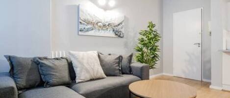A modern living room with a grey sofa, a round coffee table, and a painting on the wall.