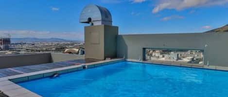A rooftop swimming pool with a clear view of the cityscape and a dome structure.