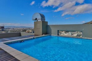 A rooftop swimming pool with a clear view of the cityscape and a dome structure.