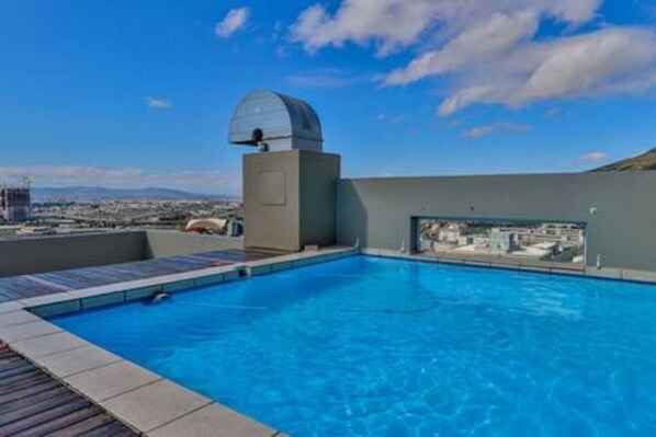 A rooftop swimming pool with a clear view of the cityscape and a dome structure.