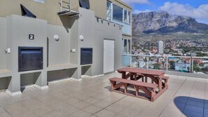 Un edificio con balcón, mesa de picnic y vista a una cadena montañosa.