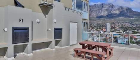 A building with a balcony, a picnic table, and a view of a mountain range.