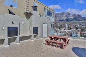 A building with a balcony, a picnic table, and a view of a mountain range.