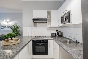 Une cuisine moderne équipée d’une cuisinière à gaz, d’un four et d’un évier en acier inoxydable.