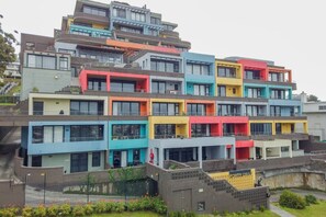 A multi-story residential building with balconies and a staircase leading to the upper levels.