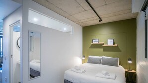 Ett modernt sovrum med en stor säng, sänglampor, en spegel och utsikt över omgivningen.