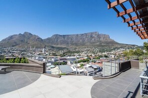 A rooftop terrace with a view of a cityscape and mountains.