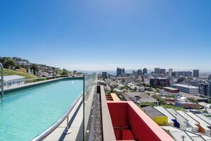 A rooftop pool with a city view, surrounded by buildings and a clear sky.