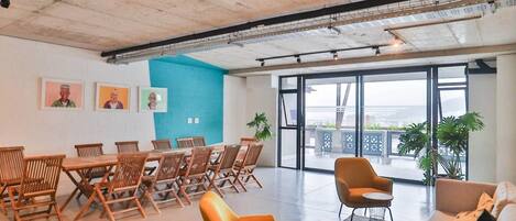 A spacious room with a long table and chairs, a sofa, and a large window with a view.