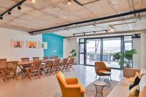 A spacious room with a long table and chairs, a sofa, and a large window with a view.