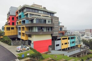 A multi-story residential building with balconies and a car parked in front.