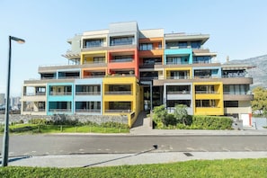 A multi-story residential building with balconies, a flat roof, and a clear sky.
