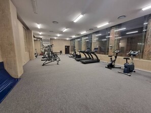 A gym with exercise equipment, including treadmills and weight machines, and a mirrored wall.
