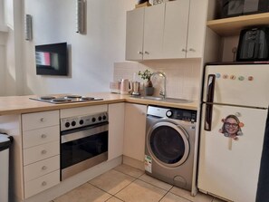 A compact kitchen with a stove, oven, microwave, and washing machine.