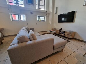 A living room with a sofa, a television, and a small table with books.