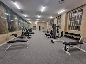A gym with exercise equipment, benches, and dumbbells.