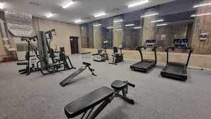 A gym with various exercise equipment including treadmills, a bench press, and weight machines. - Stylish City Studio | High ceilings & gym by ctha (Cape Town)