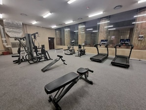 Una palestra con diverse attrezzature per esercizi, tra cui tapis roulant, panca piana e macchinari per pesi.