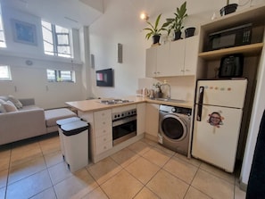 A compact kitchen with a washing machine, microwave, and a sink.